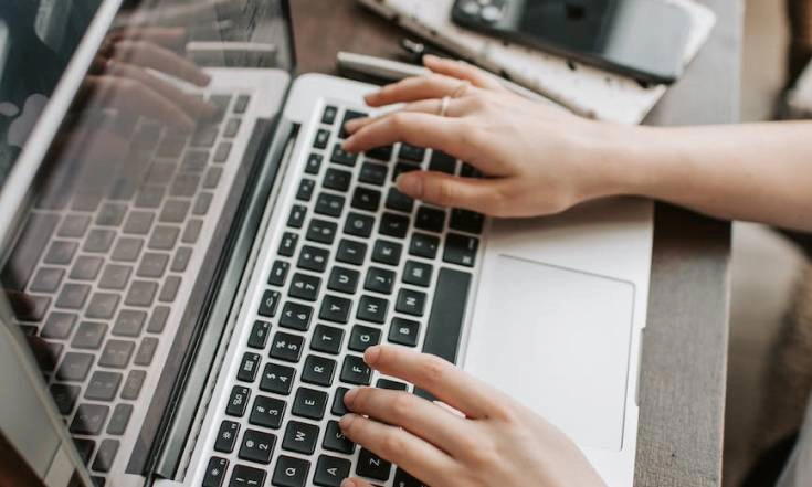 Photo of hands using laptop keyboard