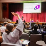 Attendees raising hands in auditorium